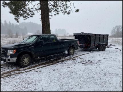 A truck with a dump trailer in the snow