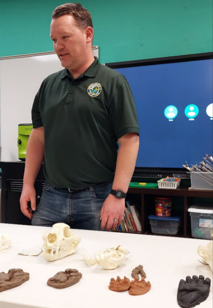 Biologist Cook in front of a table with skulls and rubber scat